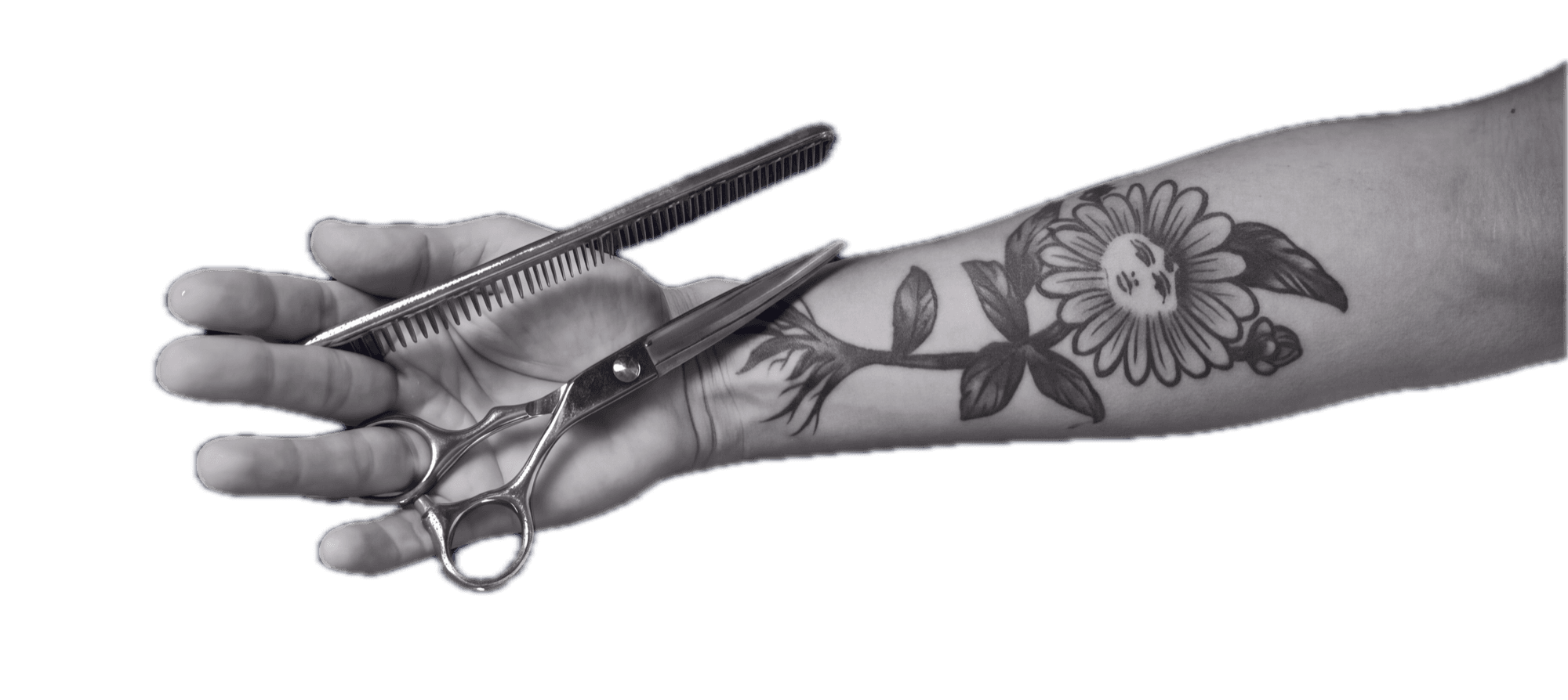 Tattooed hand holding scissors and a comb